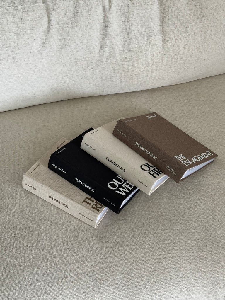 Linen-bound wedding albums titled The Rehearsal, Our Wedding, Our First Year and The Engagement
