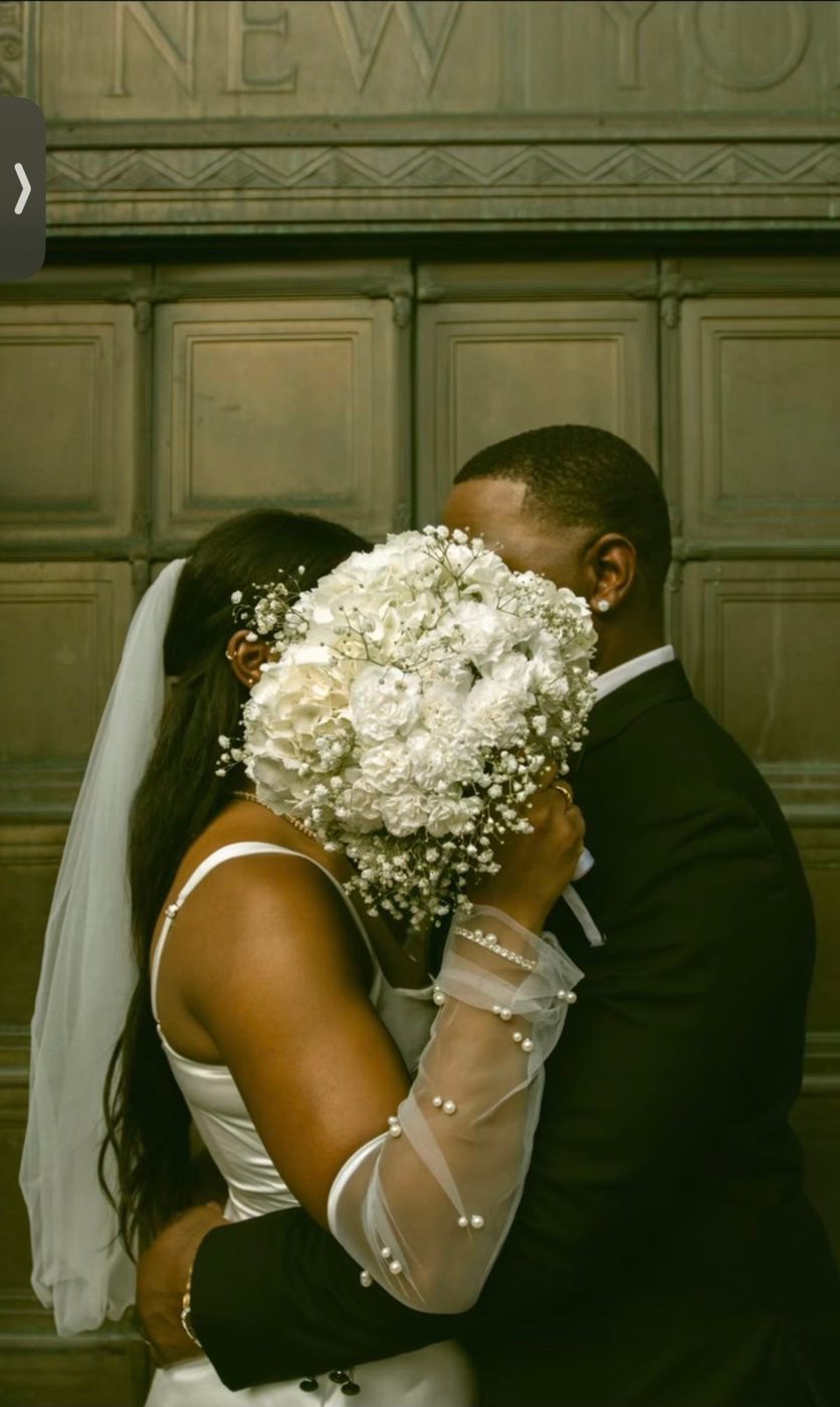 A couple embracing, the bride's bouquet of white flowers between them