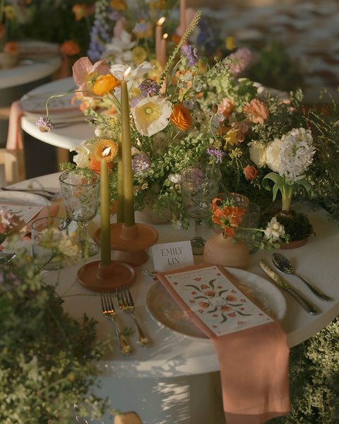 A styled reception table with candles, flowers and a printed menu