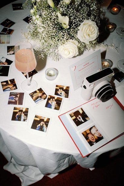 A guest table with instant photos, a camera and a guestbook