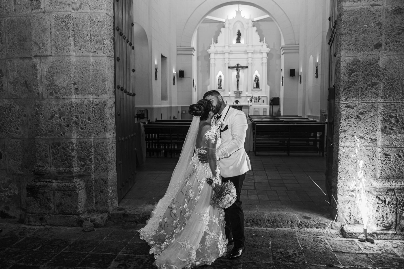 A couple kissing in the doorway of a church, in black and white